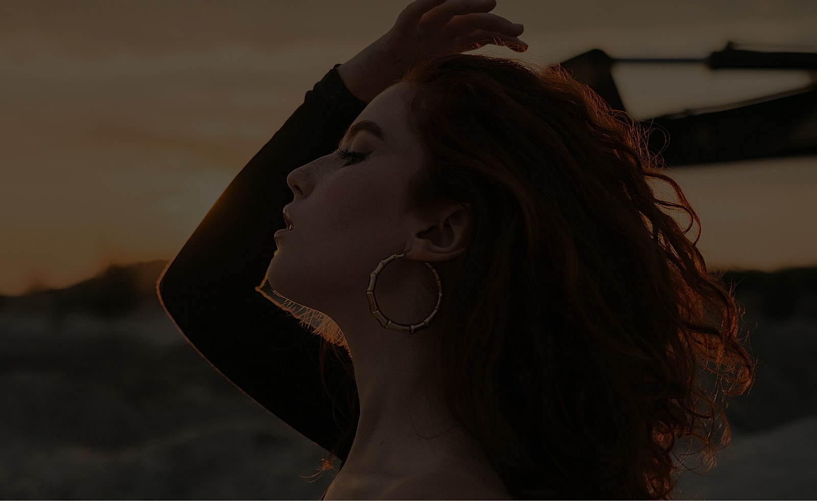Woman with curly hair at sunset silhouette.