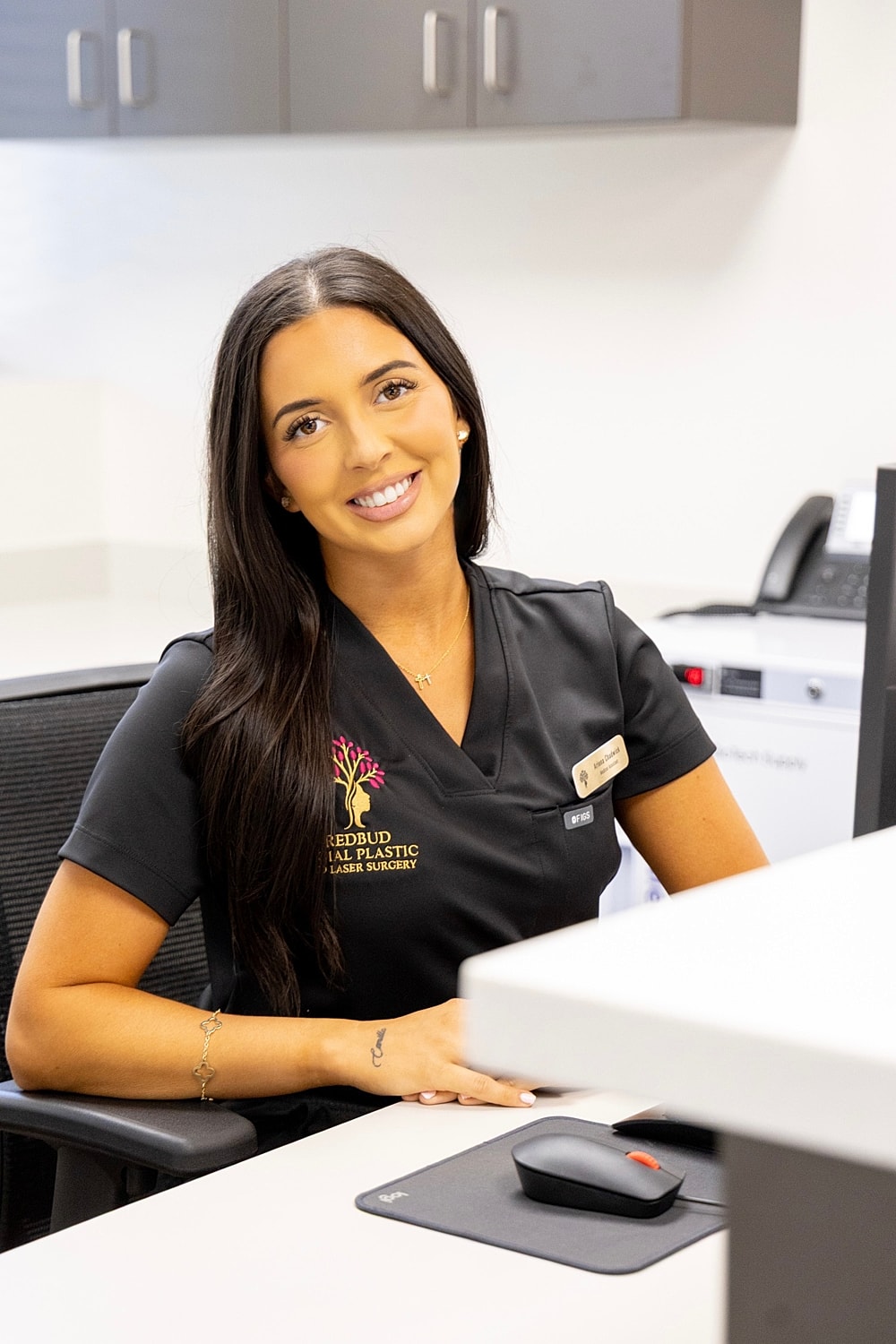 Smiling professional at a medical office receptionist desk.