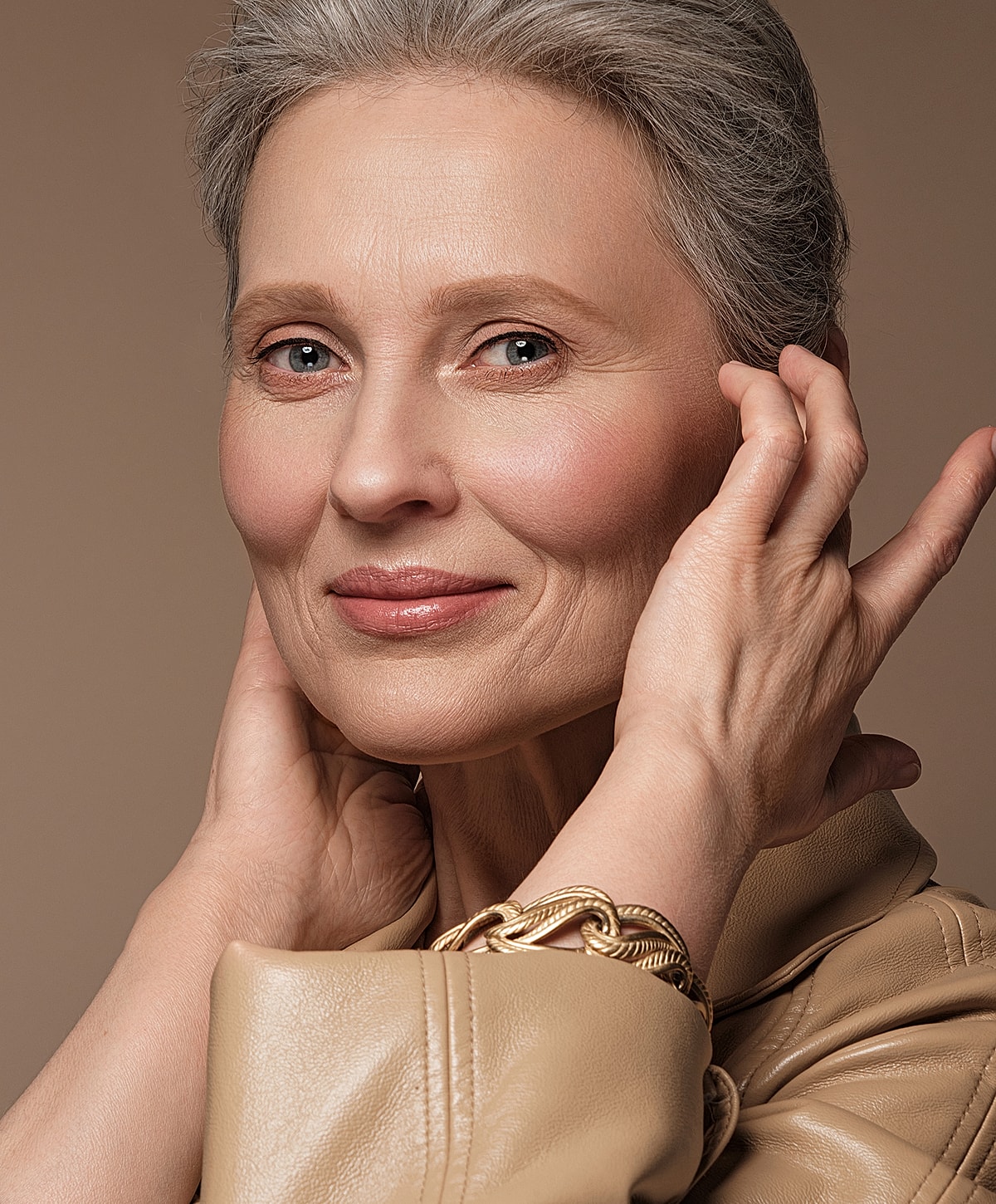 Elegant older woman with silver hair and jewelry.