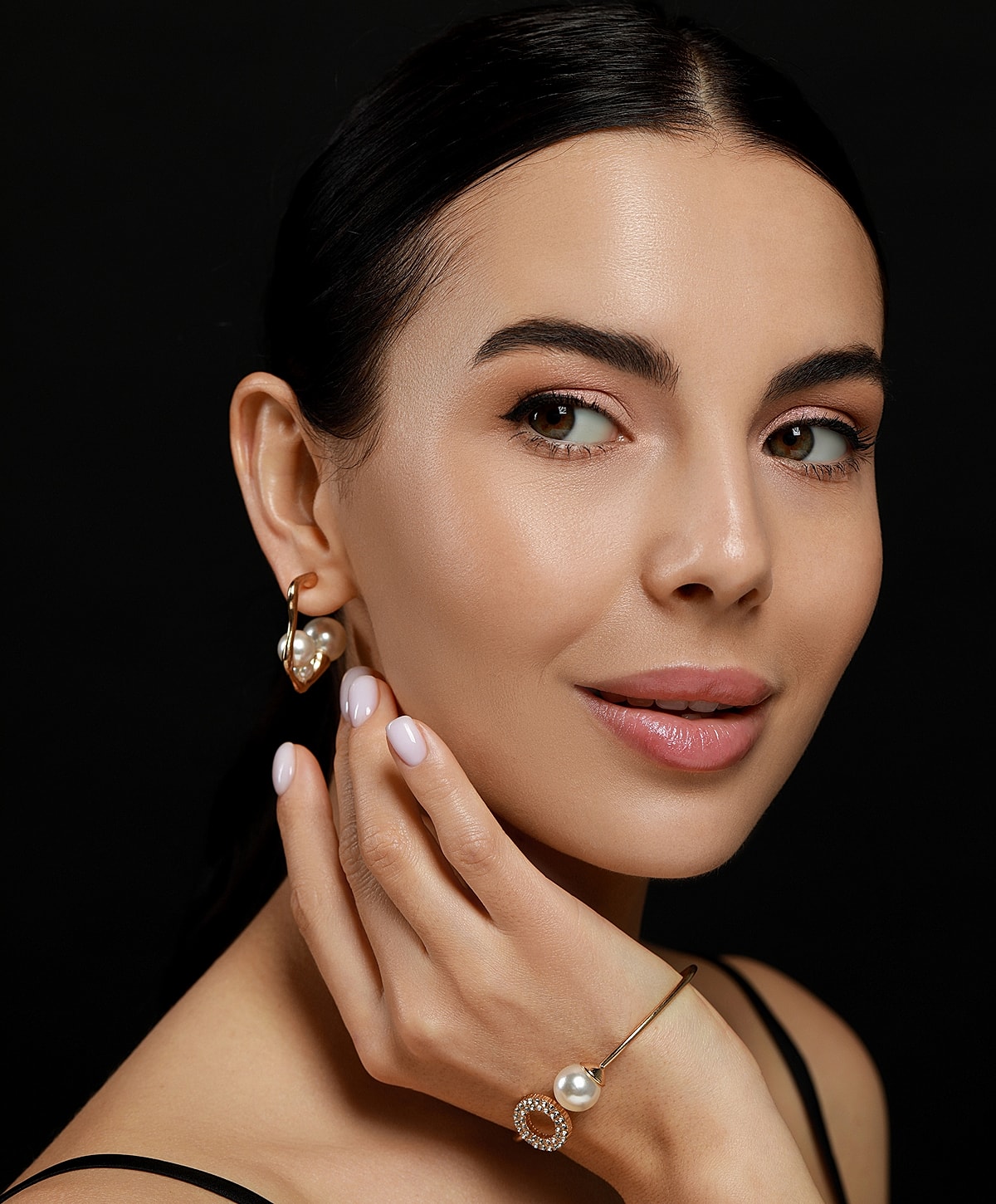 Woman wearing elegant jewelry against a black background.
