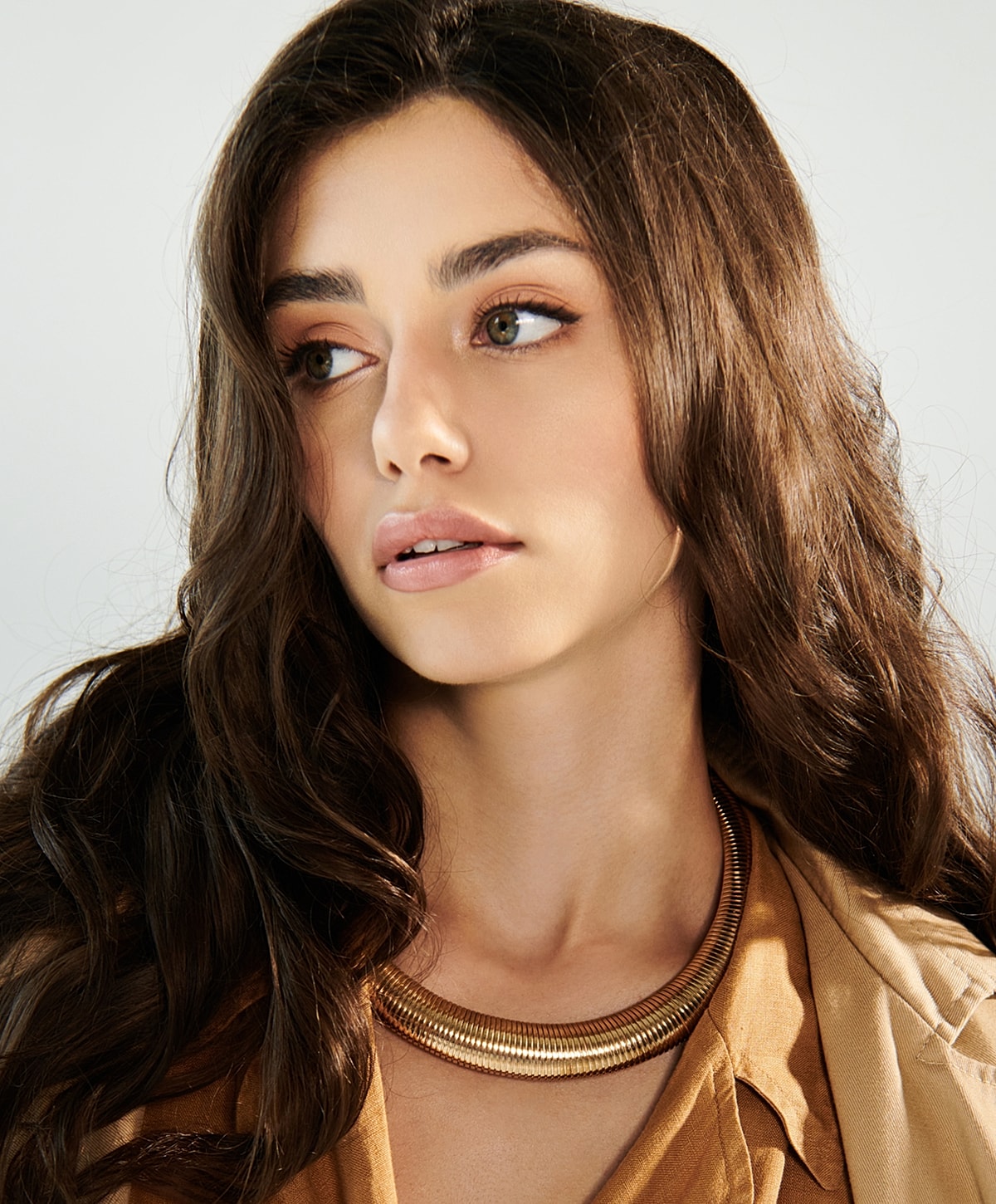 Woman with wavy hair wearing a statement necklace.