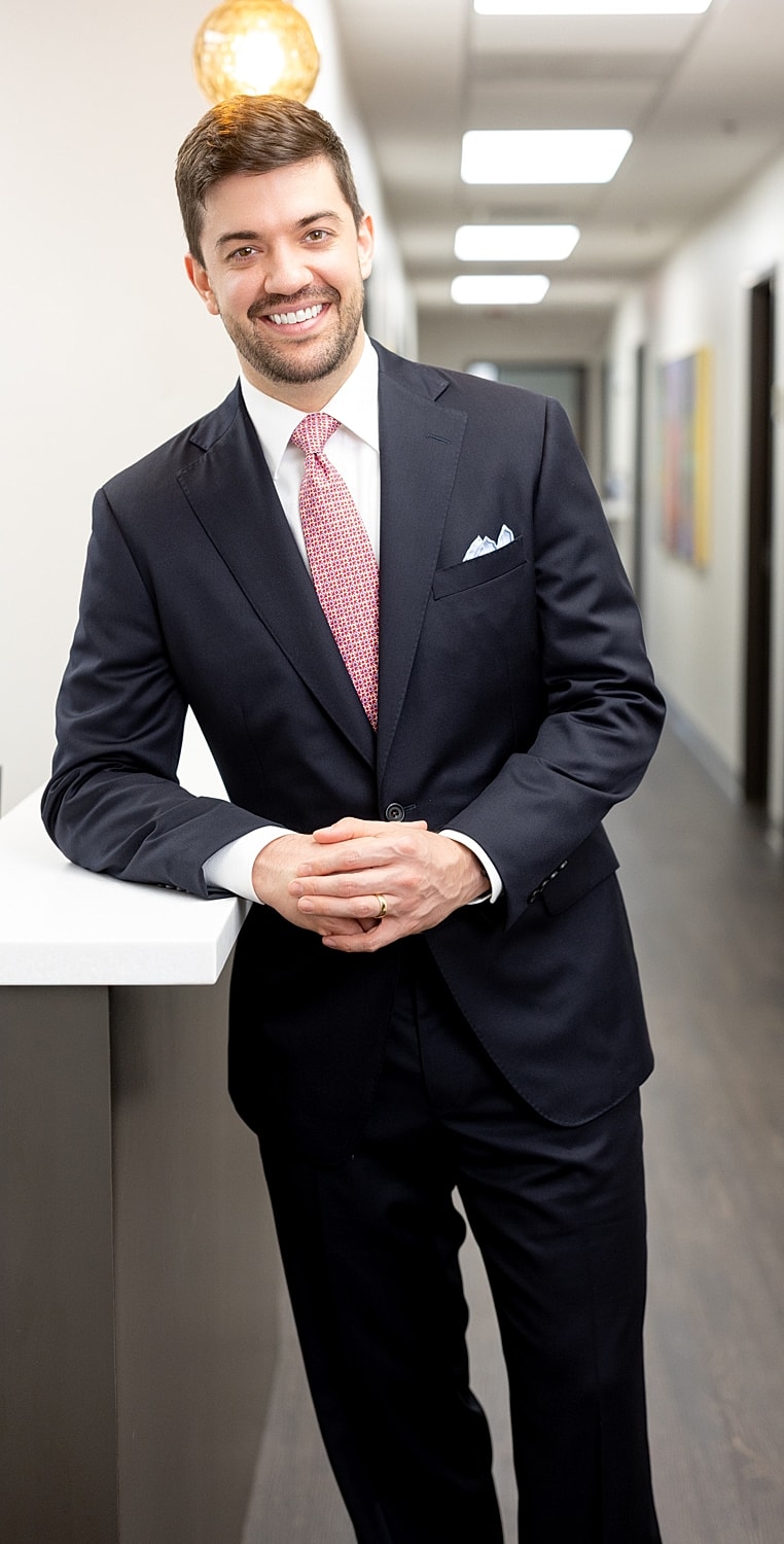 Man in suit smiling in office setting.