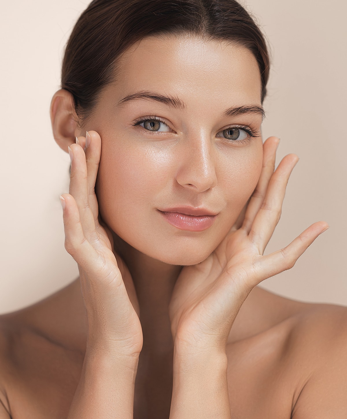 Woman gently touching her face, soft lighting.