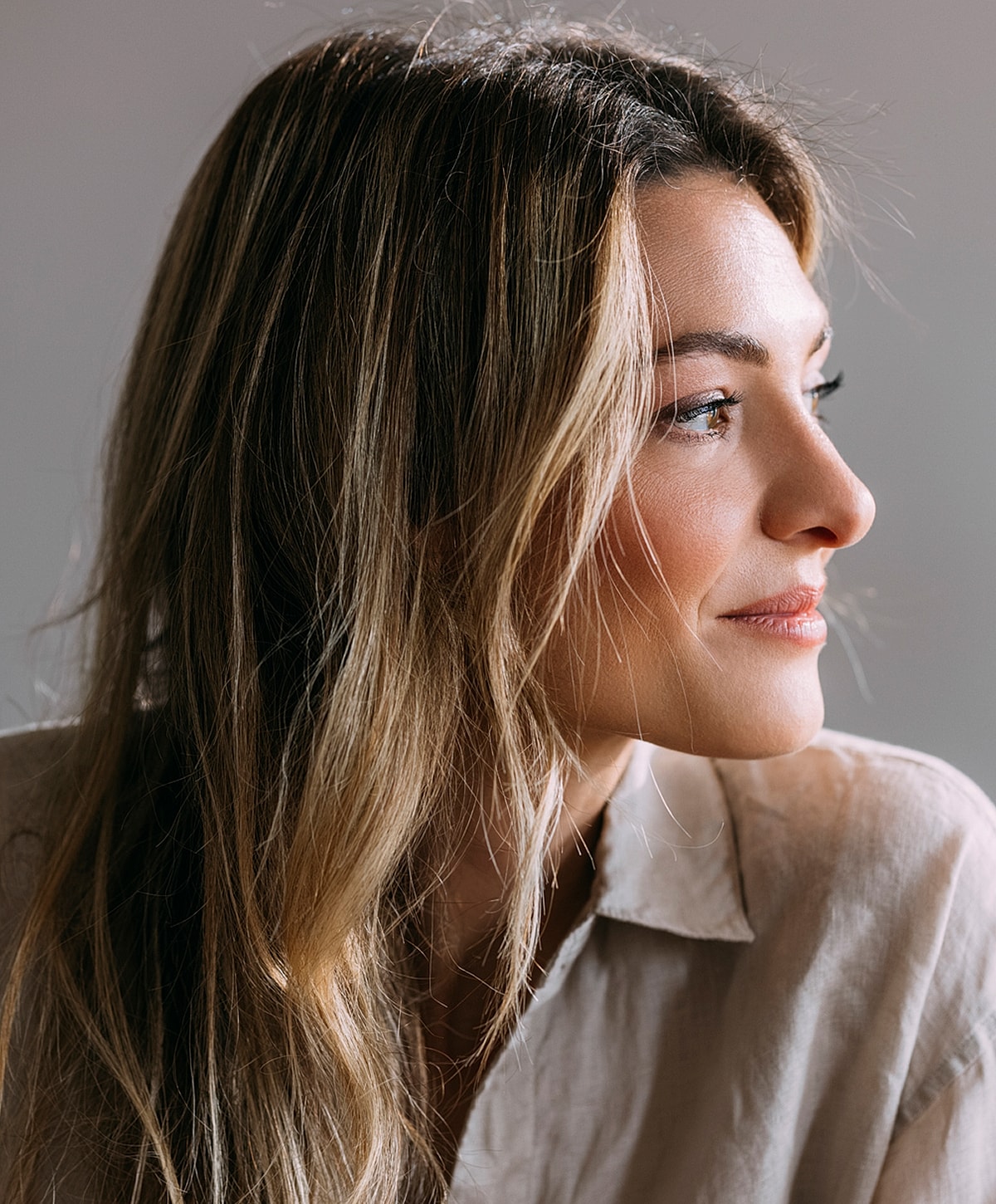 Woman with long hair gazing thoughtfully to side.