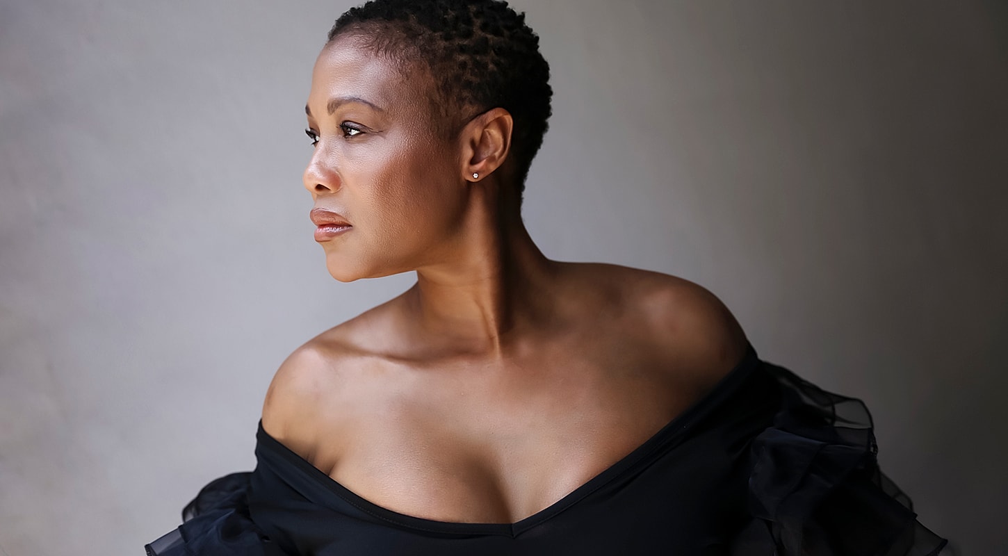 Woman in black dress, looking thoughtfully to side.