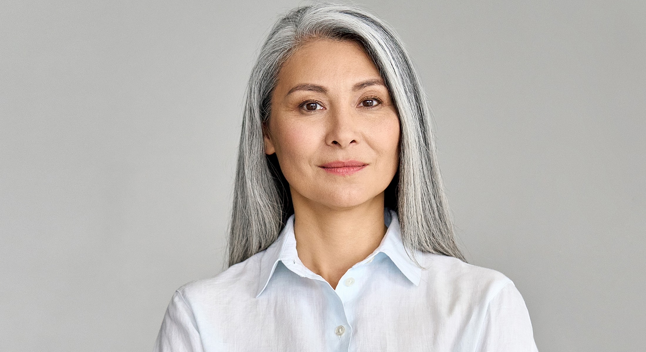 Woman with gray hair in a light-colored blouse.